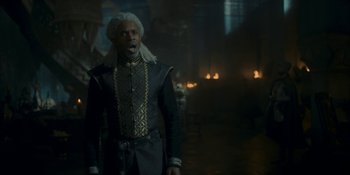 Movie still from “House of the Dragon” (2022), created by George R.R. Martin – A man with a white hat and a black and gold jacket; Medium shot, Low angle