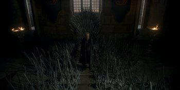 Movie still from “House of the Dragon” (2022), created by George R.R. Martin – A man sitting on a throne in front of a bunch of trees; Wide shot, High angle