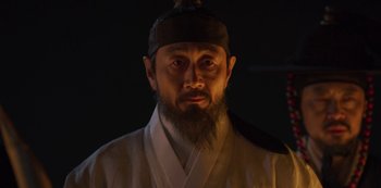 Movie still from “Kingdom” (2019), created by Eun-hee Kim – A man with a long beard wearing a black hat; Close Up shot, Low angle