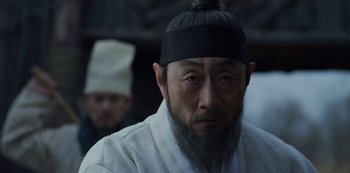 Movie still from “Kingdom” (2019), created by Eun-hee Kim – A man with a long beard wearing a black hat; Close Up shot, Low angle