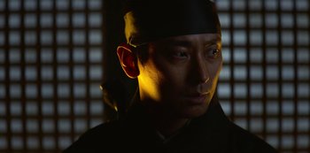 Movie still from “Kingdom” (2019), created by Eun-hee Kim – A person wearing a hat; Close Up shot, Low angle