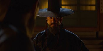 Movie still from “Kingdom” (2019), created by Eun-hee Kim – A man wearing a black hat and a beard; Close Up shot, Low angle