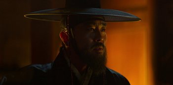 Movie still from “Kingdom” (2019), created by Eun-hee Kim – A man with a beard wearing a hat; Close Up shot, Low angle