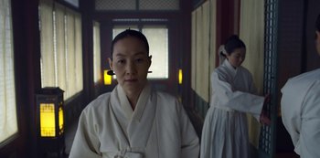 Movie still from “Kingdom” (2019), created by Eun-hee Kim – A woman in a white robe standing next to another woman; Medium shot, Low angle