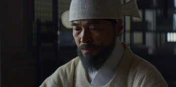 Movie still from “Kingdom” (2019), created by Eun-hee Kim – A man with a beard wearing a white hat; Close Up shot, Low angle