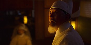 Movie still from “Kingdom” (2019), created by Eun-hee Kim – A man with a white beard wearing a white hat; Close Up shot, Low angle