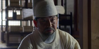 Movie still from “Kingdom” (2019), created by Eun-hee Kim – An older man wearing a white hat and a white shirt; Close Up shot, Low angle
