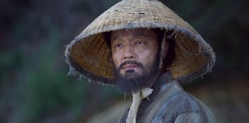 Movie still from “Kingdom” (2019), created by Eun-hee Kim – A man wearing a straw hat and a beard; Close Up shot, Low angle