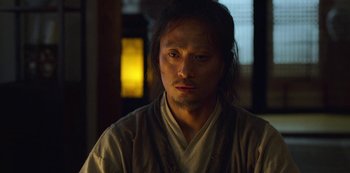 Movie still from “Kingdom” (2019), created by Eun-hee Kim – A man with long black hair wearing a white robe; Close Up shot, Low angle
