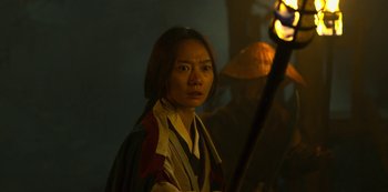 Movie still from “Kingdom” (2019), created by Eun-hee Kim – A woman is holding a torch in the dark; Medium shot, Over the shoulder angle