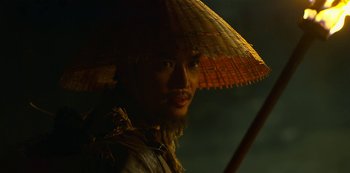 Movie still from “Kingdom” (2019), created by Eun-hee Kim – A man wearing a straw hat and holding a stick; Close Up shot, Low angle