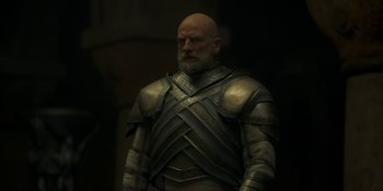 Movie still from “House of the Dragon” (2022), created by George R.R. Martin – A man with a bald head wearing armor; Medium shot, Low angle