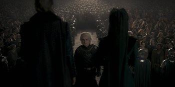 Movie still from “House of the Dragon” (2022), created by George R.R. Martin – A group of people standing in the middle of a street; Medium shot, Over the shoulder angle