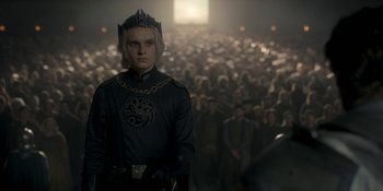 Movie still from “House of the Dragon” (2022), created by George R.R. Martin – A man wearing a crown standing in front of a crowd; Medium shot, High angle