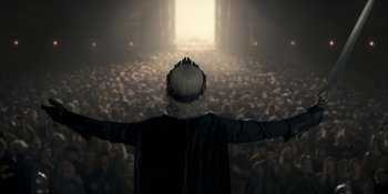 Movie still from “House of the Dragon” (2022), created by George R.R. Martin – A man in a crowd of people standing in front of an open door; Wide shot, High angle