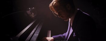 Movie still from “La La Land” (2016), directed by Damien Chazelle – A man sitting at a piano in a dark room; Medium shot, Over the shoulder angle