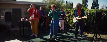 Movie still from “La La Land” (2016), directed by Damien Chazelle – A group of people standing around a microphone on a stage; Wide shot, High angle