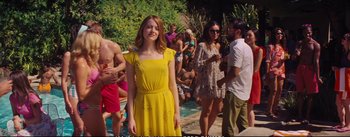 Movie still from “La La Land” (2016), directed by Damien Chazelle – A woman in a yellow dress standing in front of a group of people; Medium shot, Over the shoulder angle