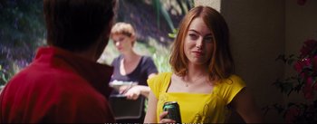 Movie still from “La La Land” (2016), directed by Damien Chazelle – A woman in a yellow dress holding a cell phone; Medium shot, Over the shoulder angle