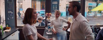 Movie still from “La La Land” (2016), directed by Damien Chazelle – Two women and a man are talking to each other; Medium shot, Over the shoulder angle