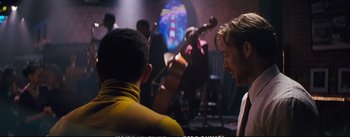 Movie still from “La La Land” (2016), directed by Damien Chazelle – A group of people in a room with a guitar; Medium shot, Over the shoulder angle