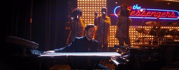 Movie still from “La La Land” (2016), directed by Damien Chazelle – A man sitting at a piano in front of a group of people; Wide shot, High angle
