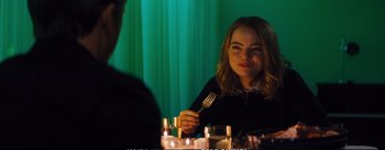 Movie still from “La La Land” (2016), directed by Damien Chazelle – A woman sitting at a table with a fork in her hand; Medium shot, Over the shoulder angle