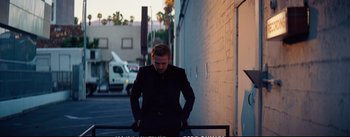 Movie still from “La La Land” (2016), directed by Damien Chazelle – A man in a suit leaning against a wall; Medium shot, Over the shoulder angle