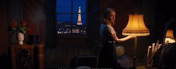 Movie still from “La La Land” (2016), directed by Damien Chazelle – A woman standing in front of a window with a view of the eiffel tower in the distance; Wide shot, Over the shoulder angle