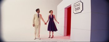 Movie still from “La La Land” (2016), directed by Damien Chazelle – A man and a woman holding hands in front of a building; Wide shot, Low angle