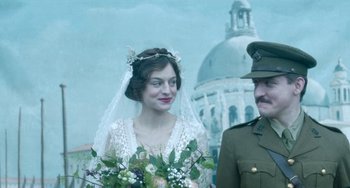 Movie still from “Lady Chatterley's Lover” (2022), directed by Laure de Clermont-Tonnerre – A woman in a white dress holding a bouquet of flowers next to a man in a uniform; Medium shot, Low angle
