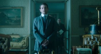 Movie still from “Lady Chatterley's Lover” (2022), directed by Laure de Clermont-Tonnerre – A man in a suit standing in front of another man in a suit; Medium shot, Low angle