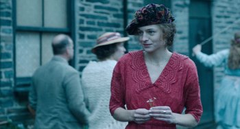 Movie still from “Lady Chatterley's Lover” (2022), directed by Laure de Clermont-Tonnerre – A woman in a red dress holding a flower in her hand; Medium shot, Over the shoulder angle