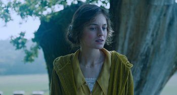 Movie still from “Lady Chatterley's Lover” (2022), directed by Laure de Clermont-Tonnerre – A young woman in a yellow coat standing next to a tree; Close Up shot, Over the shoulder angle