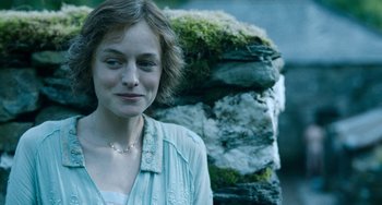 Movie still from “Lady Chatterley's Lover” (2022), directed by Laure de Clermont-Tonnerre – A woman standing next to a pile of rocks; Close Up shot, Over the shoulder angle