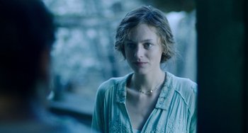 Movie still from “Lady Chatterley's Lover” (2022), directed by Laure de Clermont-Tonnerre – A woman in a blue shirt is looking at the camera; Close Up shot, Over the shoulder angle