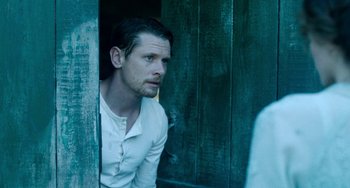 Movie still from “Lady Chatterley's Lover” (2022), directed by Laure de Clermont-Tonnerre – A man in a white shirt looking out of a door; Medium shot, High angle