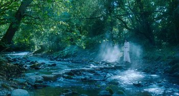 Movie still from “Lady Chatterley's Lover” (2022), directed by Laure de Clermont-Tonnerre – A person standing in the middle of a stream; Extreme Wide shot, High angle