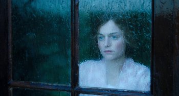 Movie still from “Lady Chatterley's Lover” (2022), directed by Laure de Clermont-Tonnerre – A woman looking out of a window at the rain; Close Up shot, High angle