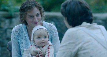 Movie still from “Lady Chatterley's Lover” (2022), directed by Laure de Clermont-Tonnerre – A woman holding a baby in her arms; Close Up shot, Over the shoulder angle