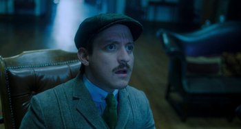 Movie still from “Lady Chatterley's Lover” (2022), directed by Laure de Clermont-Tonnerre – A man with a mustache wearing a hat and a tie; Close Up shot, Low angle