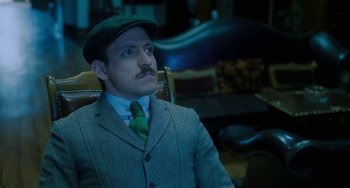 Movie still from “Lady Chatterley's Lover” (2022), directed by Laure de Clermont-Tonnerre – A man in a suit and tie sitting in a chair; Close Up shot, Low angle