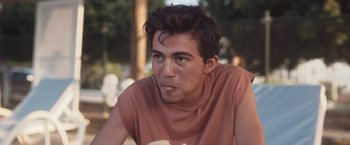 Movie still from “Last Summer” (2021), directed by Ozan Açiktan – A young man sitting in front of a tree; Close Up shot, Low angle