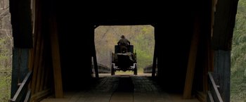Movie still from “Lawless” (2012), directed by John Hillcoat – A man riding in a horse - drawn carriage through a tunnel; Wide shot, Low angle