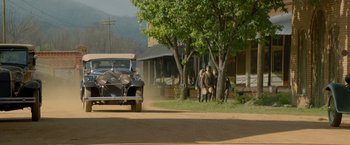 Movie still from “Lawless” (2012), directed by John Hillcoat – Two men are walking down the street while a car drives by; Extreme Wide shot, High angle