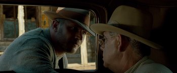 Movie still from “Lawless” (2012), directed by John Hillcoat – A man in a cowboy hat looking into a mirror; Close Up shot, Over the shoulder angle