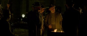 Movie still from “Lawless” (2012), directed by John Hillcoat – A group of men standing around a fire at night; Medium shot, Over the shoulder angle