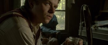 Movie still from “Lawless” (2012), directed by John Hillcoat – A man sitting in front of a window holding a jar; Close Up shot, Low angle