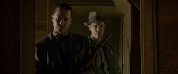 Movie still from “Lawless” (2012), directed by John Hillcoat – A man in a suit and a man in a hat holding a gun; Close Up shot, Low angle