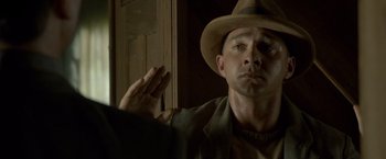 Movie still from “Lawless” (2012), directed by John Hillcoat – A man wearing a hat is looking at the camera; Close Up shot, Low angle
